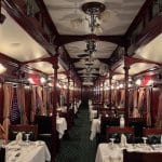 Voiture-restaurant de l'African Explorer avec tables dressées, boiseries acajou et lustres élégants