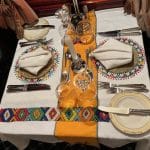 Table dressée avec art africain dans le wagon-restaurant de l'African Explorer, nappes brodées colorées